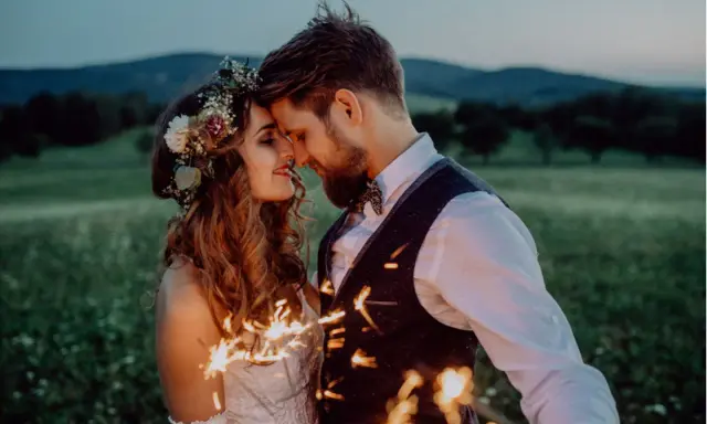 Ein Brautpaar feiert seine elopement hochzeit im Freien bei Einbruch der Dunkelheit mit Wunderkerzen.