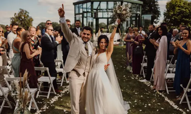 Glückliches Brautpaar feiert den Beginn des Hochzeitsablaufplans. Gäste applaudieren bei der Zeremonie im Freien.