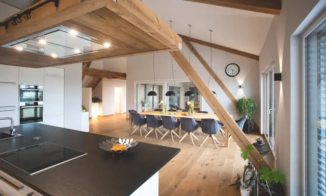 Rustikale Holzbalken und ein langer Esstisch schaffen eine gemütliche Atmosphäre, perfekt für eine Scheune Hochzeit.
