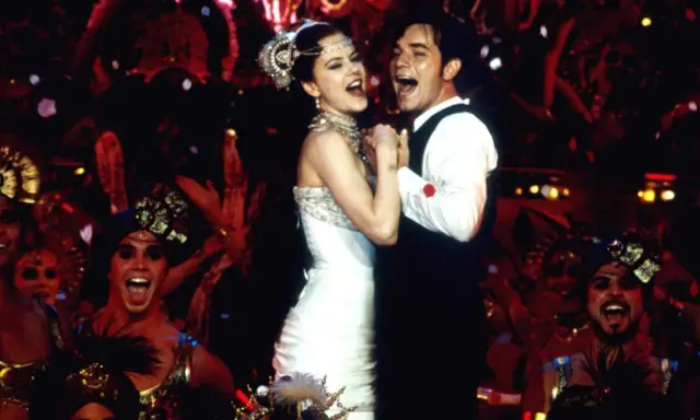 Ein glückliches Paar tanzt, umgeben von einer jubelnden Menge in Kostümen. Ein Moment, der an unvergessliche filmzitate hochzeit erinnert.