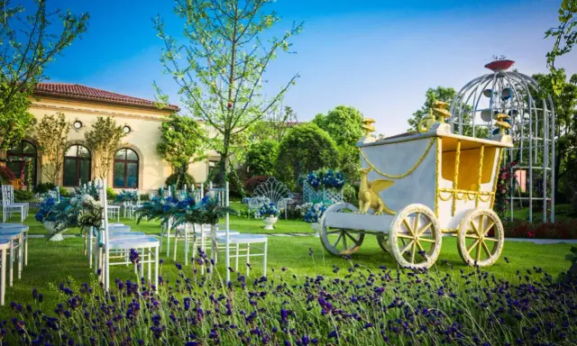 Märchenhafte Kutsche und Sitzreihen im Garten deuten auf eine unkonventionelle Hochzeit hin.