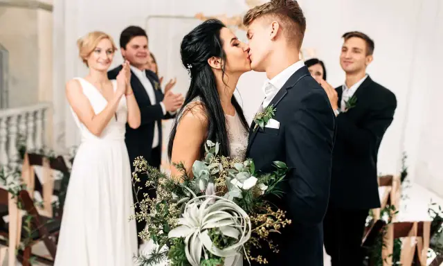 Brautpaar küsst sich, Gäste applaudieren. Der Beginn der standesamtlichen hochzeit ablauf ist ein emotionaler Moment.