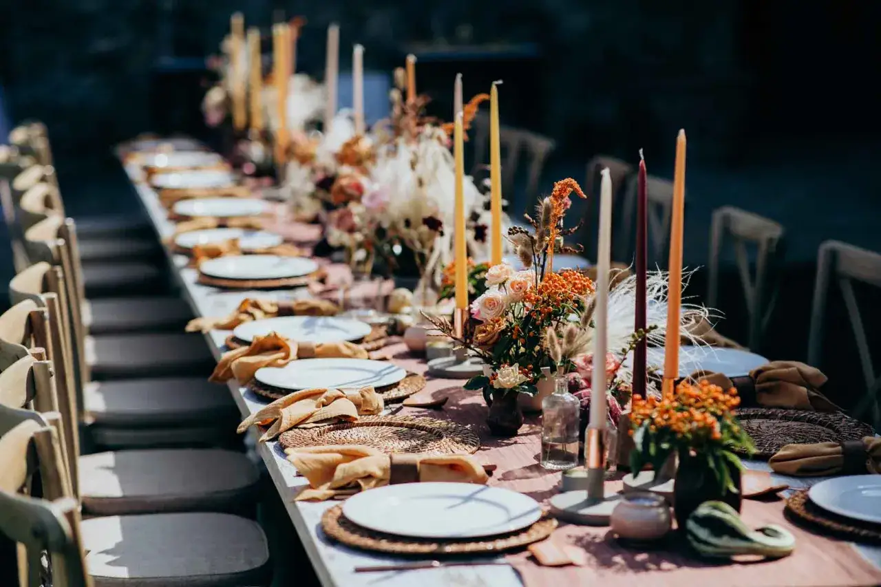 Festliche tischdeko hochzeit herbst mit Kerzen, Blumen und Stoffservietten in warmen T&ouml;nen.