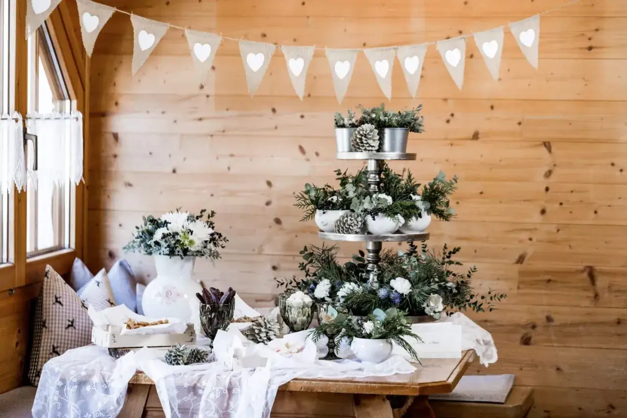 Festliche Deko für eine Hochzeit auf der Alm: Tannengrün, Zapfen und weiße Herzen schmücken den Tisch.