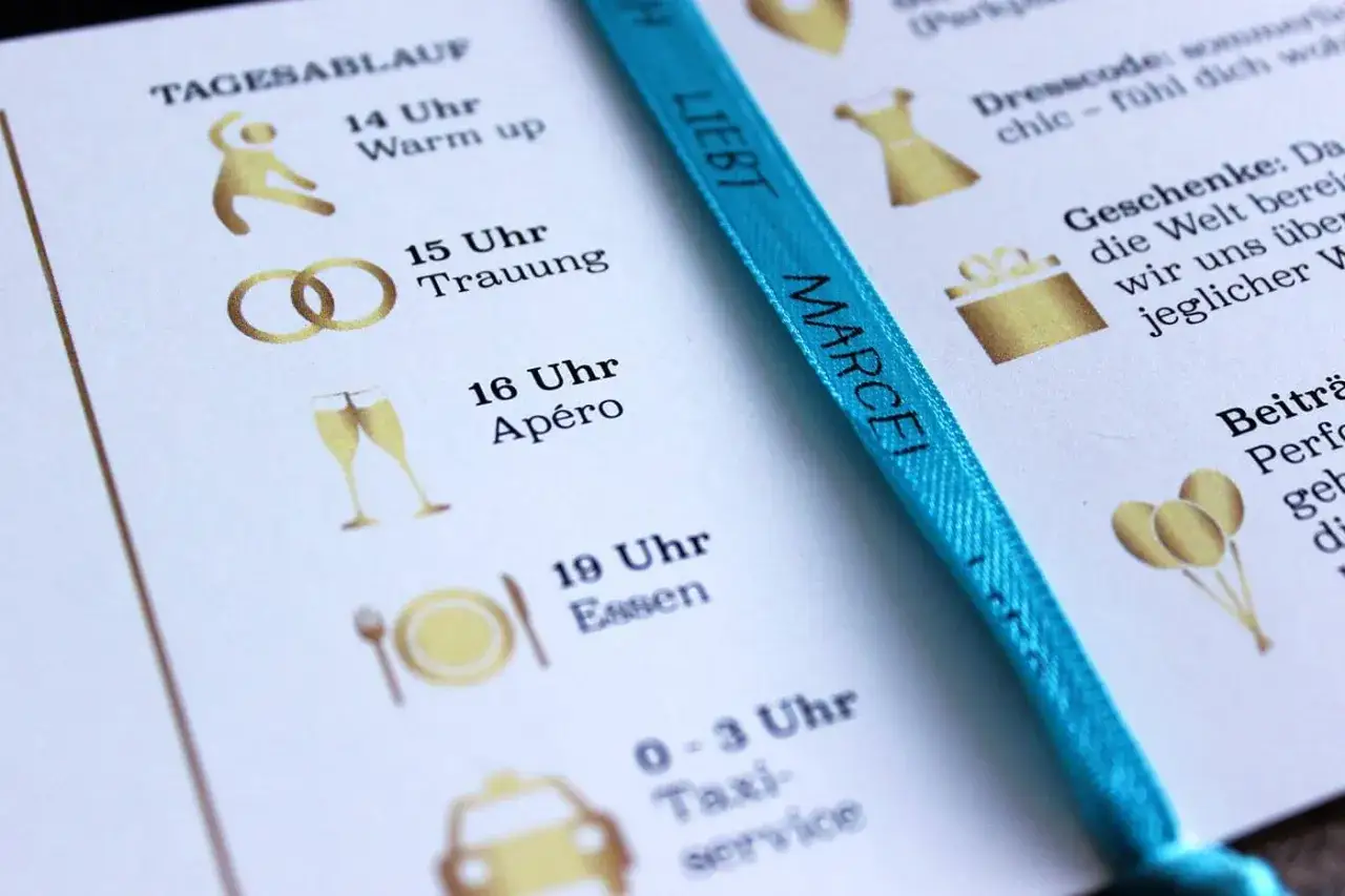 Hochzeits-Ablaufplan mit goldenen Symbolen: Warm-up, Trauung, Apéro, Essen, Taxi. Ein blauer Band mit