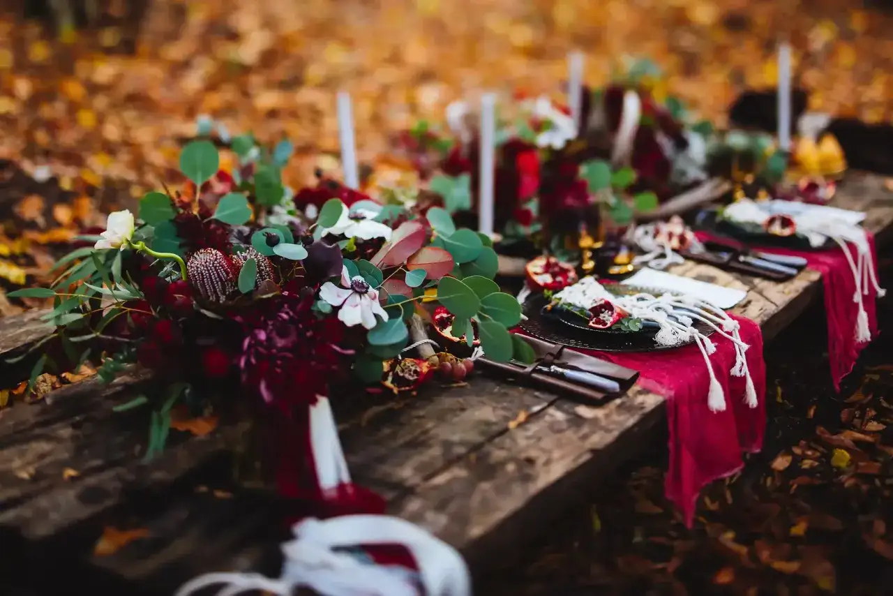 Romantische rot hochzeit Deko mit Blumen und Kerzen auf Holztisch im Herbstwald.