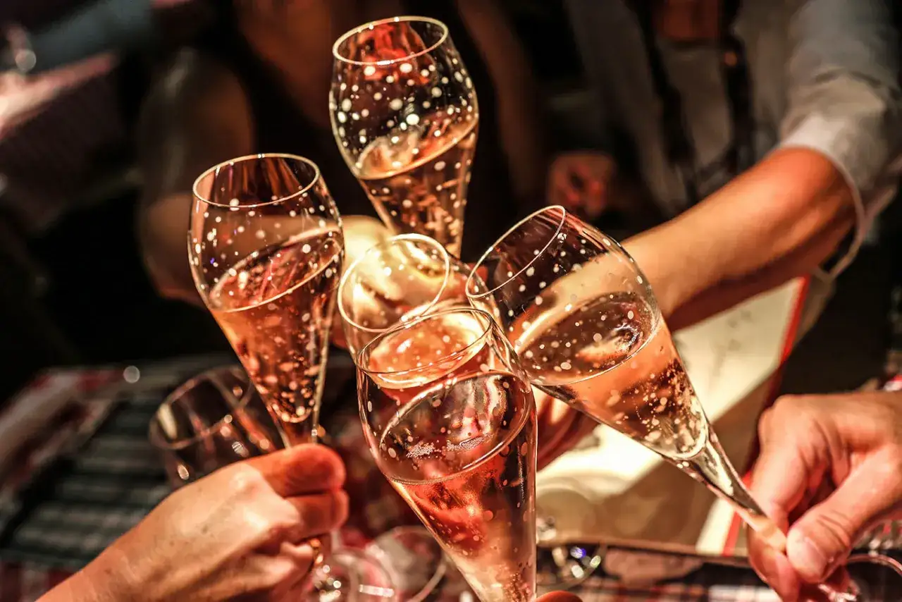 H&auml;nde halten Gl&auml;ser mit sprudelndem Ros&eacute;wein, um einen Toast auszusprechen.
