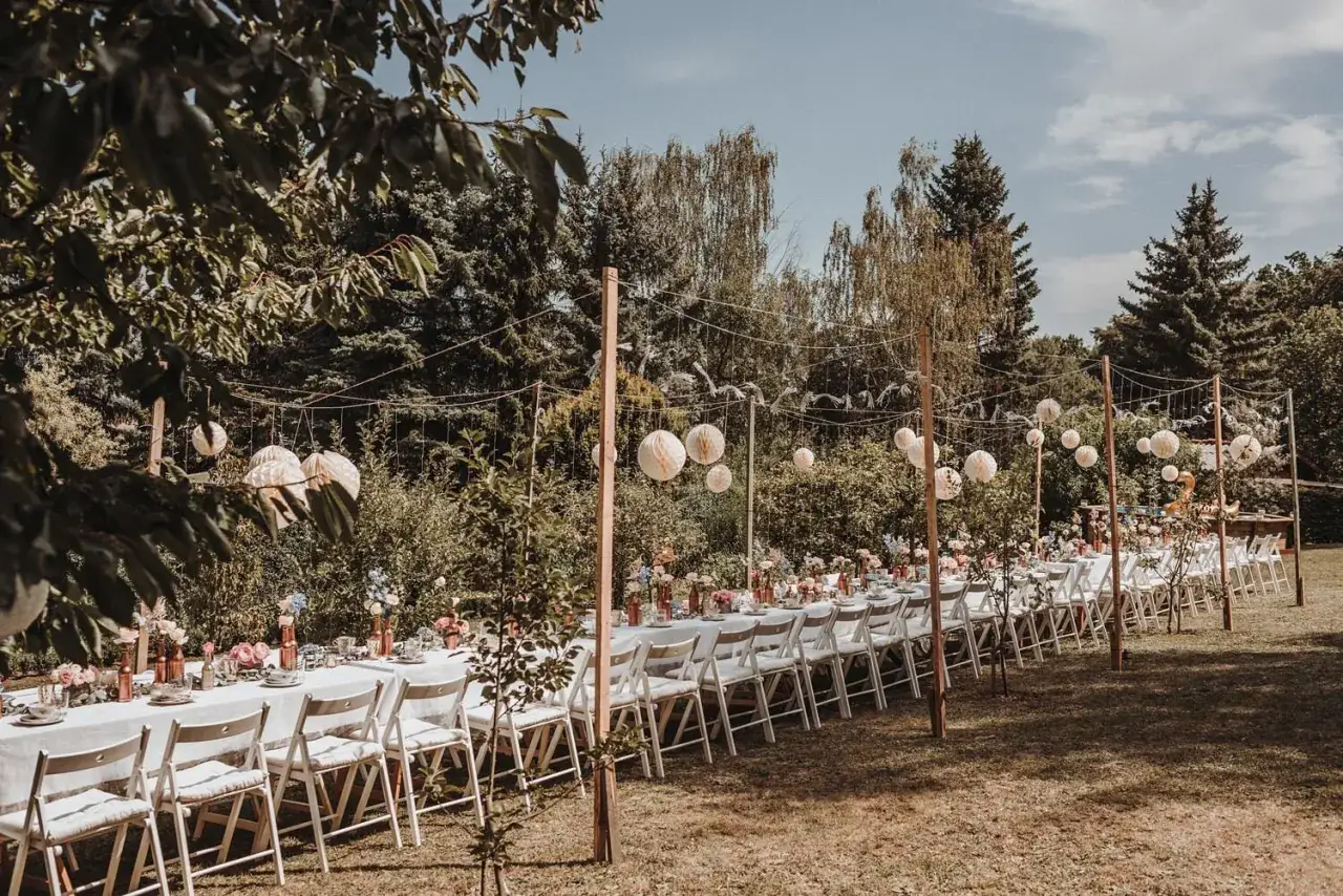 Festlich gedeckte Tafel f&uuml;r eine Garten Hochzeit, geschm&uuml;ckt mit Blumen und Papierlaternen.