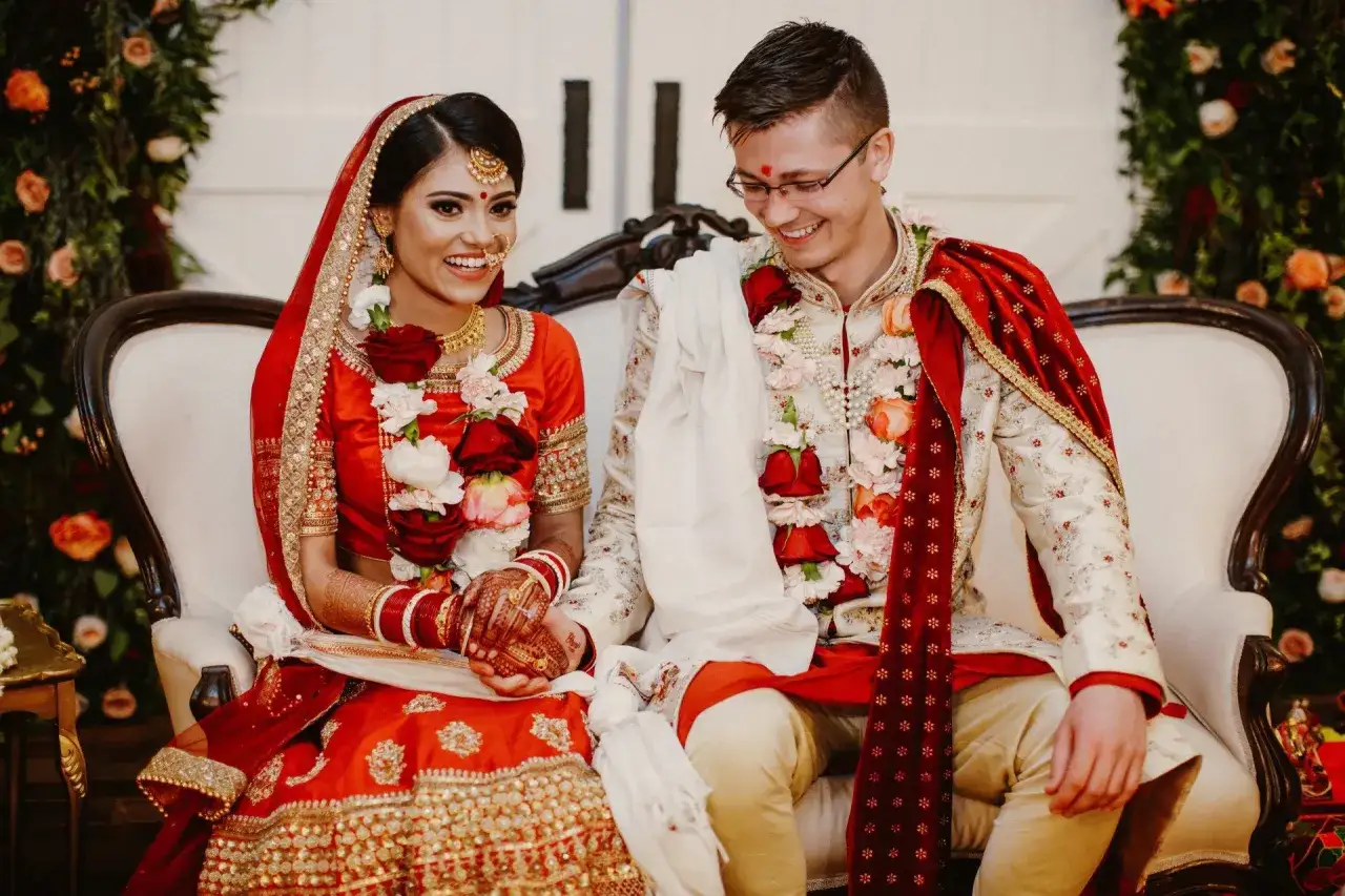 Gl&uuml;ckliches Brautpaar bei einer indischen Hochzeit, sie tragen traditionelle Kleidung und Blumengirlanden.