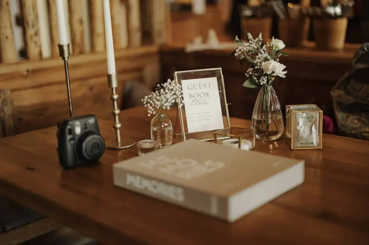 Gästebuch, Sofortbildkamera und Blumenarrangements für originelle Ideen Hochzeit. Ein Tisch voller Erinnerungen.